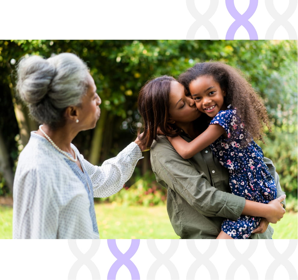 An older woman is looking at her daughter who is carrying and kissing her granddaughter.
